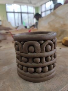 a clay vase sitting on top of a wooden table