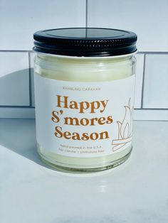 a jar of happy s'mores season candle sitting on a white counter top