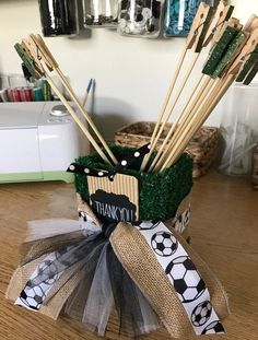 there are many wooden sticks in a basket with grass and soccer balls on the table