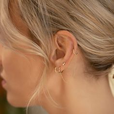 a woman with blonde hair is wearing gold ear cuffs and a pair of diamond earrings