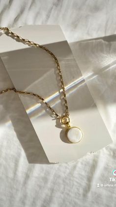 a necklace with a pearl hanging from it's side on a white piece of paper