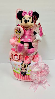 a minnie mouse figurine sitting on top of a stack of baby items with a pink bow