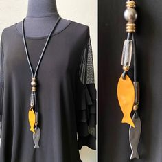 a black shirt with a yellow fish pendant on it's side and a necklace hanging from the back