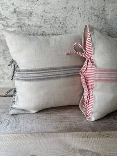 two gray and pink striped pillows sitting on top of a wooden table next to each other