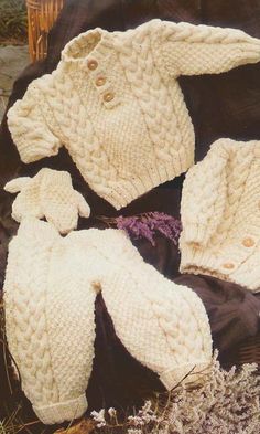 three knitted sweaters and hats sitting on the ground