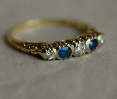 three stone gold ring with blue and white stones on the side, sitting on a table