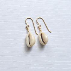 Simple & cute describe these whole cowrie shell earrings! They're the perfect accessory to wear with your favorite casual outfit when you're out & about. Please allow for variations in size and shape of shells as each is unique. Trendy Single Earring For Beach Jewelry, Trendy Single Earring For Beach, Casual Shell Jewelry Gift, Cowrie Shell Earrings For Gifts, Handmade Cowrie Shell Earrings For Gift, Handmade Cowrie Shell Earrings As Gift, Nickel-free Shell Gift, Cowrie Shell Dangle Earrings As Gift, Trendy Beach Drop Earrings