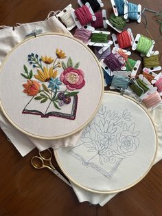 two embroidery hoops are next to each other on a table with scissors and thread