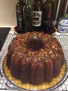 a bundt cake sitting on top of a cooling rack next to bottles of wine