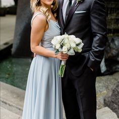 a bride and groom standing next to each other in front of a fountain with flowers