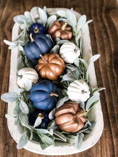 some pumpkins and leaves in a white bowl