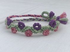 two bracelets with flowers and tassels on them sitting on a white surface