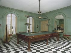 a pool table is in the middle of a room with checkered flooring and chandeliers