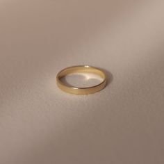 a gold ring sitting on top of a white surface with the light shining through it