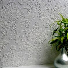 a potted plant sitting on top of a white table next to a wall paper