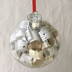 a glass ornament with musical notes hanging from it's red ribbon on a white sheet of paper