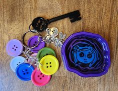 a bunch of different colored buttons sitting on top of a wooden table next to a keychain