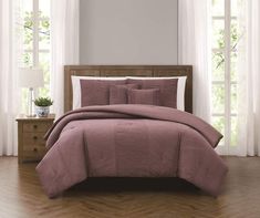 a bed with pink comforter and pillows in a room