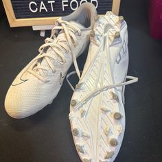 a pair of white nike shoes sitting on top of a table next to a sign