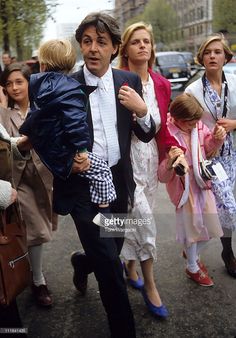 a group of people walking down the street with one holding a child in his arms