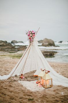 a teepee on the beach with flowers and candles