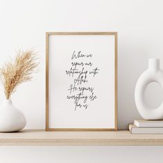 a white vase sitting on top of a wooden shelf next to a framed print with a quote