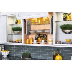 the kitchen is decorated with yellow dishes and green plants in glass shelves on the wall