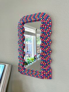 there is a mirror made out of candy balls on the wall next to a window