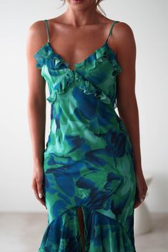 a woman wearing a green and blue dress with ruffles on the bottom,