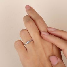 a woman's hand holding onto the finger of another person wearing a diamond ring