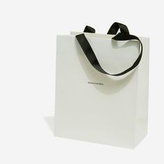 a white shopping bag with a black ribbon hanging from it's side on a white background