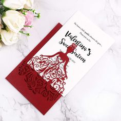 a red and white wedding card next to flowers