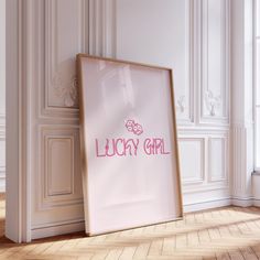 an empty frame with the word lucky girl in pink on it next to a white wall