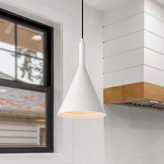 a white light hanging over a kitchen counter next to a sink and stove top oven