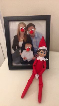 two adults and one child are posed in front of an elf's photo frame