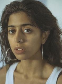 a close up of a person with ear rings on their ears and nose piercings