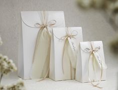 three white gift bags with ribbons tied around them