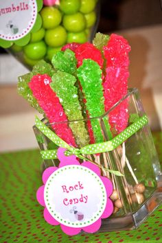 some candy sticks are in a vase on a table with green and pink candies