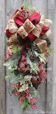 a christmas wreath hanging on the side of a wooden fence with pine cones and berries