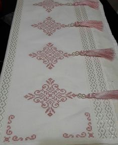 the table cloth has tassels on it and is white with pink trimming