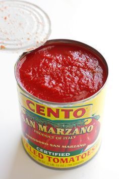 a can of tomato sauce sitting on top of a white table next to a plastic container