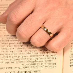 a person's hand with a ring on top of an open book