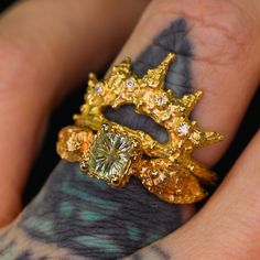 a close up of a person's hand holding a gold ring with diamonds on it