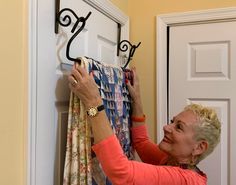 a woman is hanging clothes on a rack with two pairs of scissors in front of her