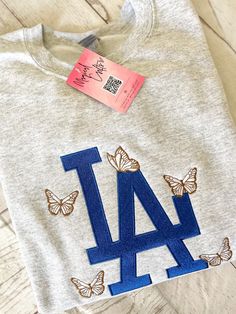 LA Butterfly Embroidered Crewneck Sweatshirt - Ash | Size up for a loose fit Varsity Tops With Embroidered Graphics And Relaxed Fit, Fall College Embroidered T-shirt, Varsity Style Embroidered Tops For College, Embroidered Oversized Tops For Loungewear, Oversized Embroidered Tops For Loungewear, Embroidered Relaxed Fit College T-shirt, Custom Embroidery Loungewear Tops, Custom Embroidered Relaxed Fit Tops For Loungewear, Relaxed Fit Tops With Custom Embroidery For Loungewear