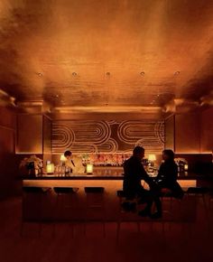 two people sitting at a bar in a dimly lit room