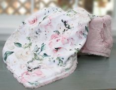 two baby blankets laying on top of a table next to each other, one pink and the other white