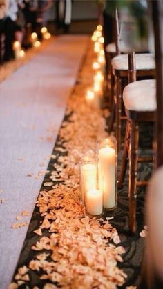 candles are lined up on the ground next to chairs