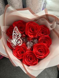 a bouquet of red roses in the shape of a heart with a butterfly on it