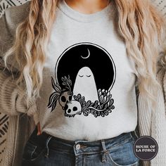 a woman wearing a t - shirt with an image of a ghost and skulls on it